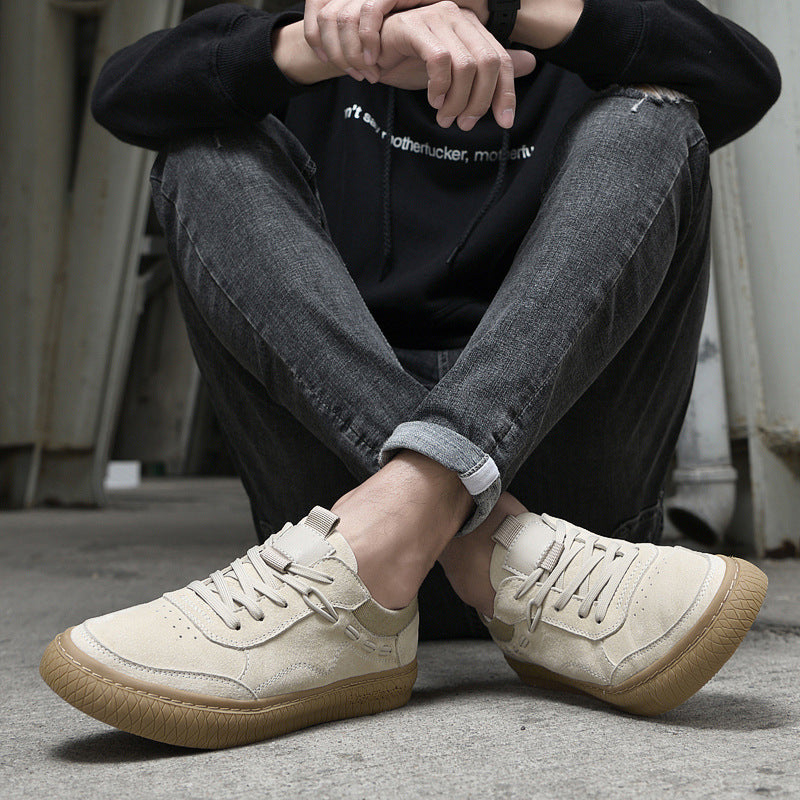 Person wearing beige sneakers with brown soles sitting on the floor.