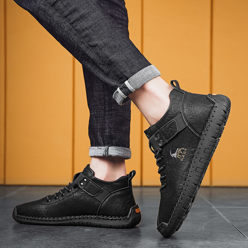 Person wearing black leather shoes with a brand logo on a yellow background