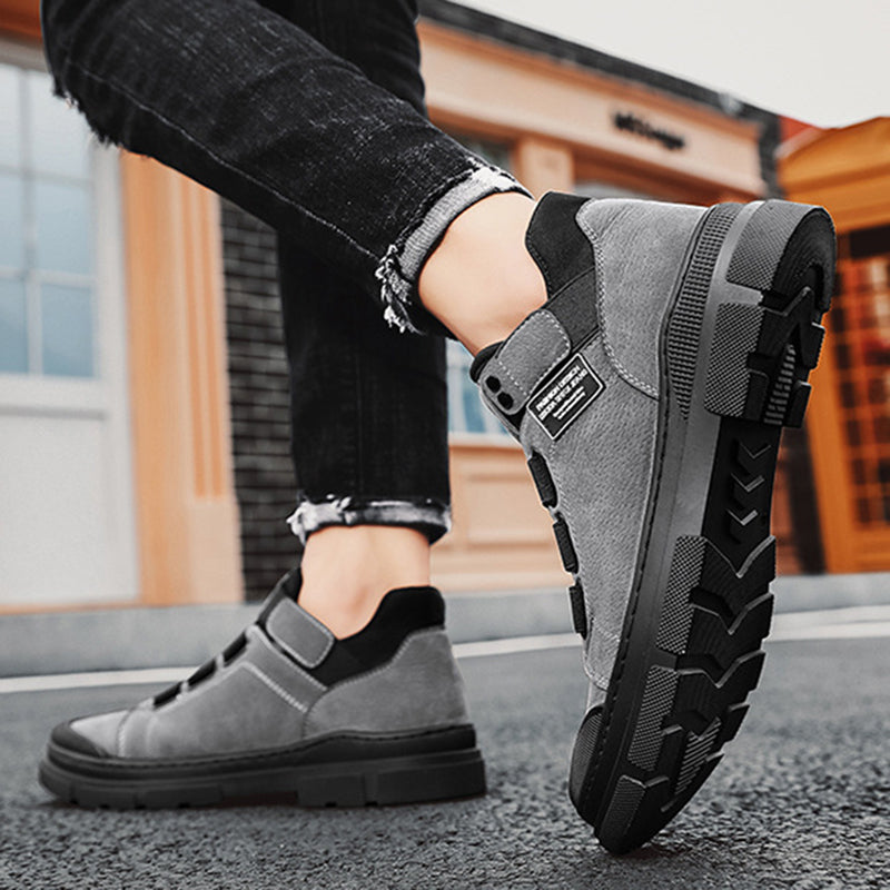 Person wearing gray slip-on boots with black soles on a street.
