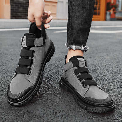 Person wearing gray sneakers with black velcro straps on a street.