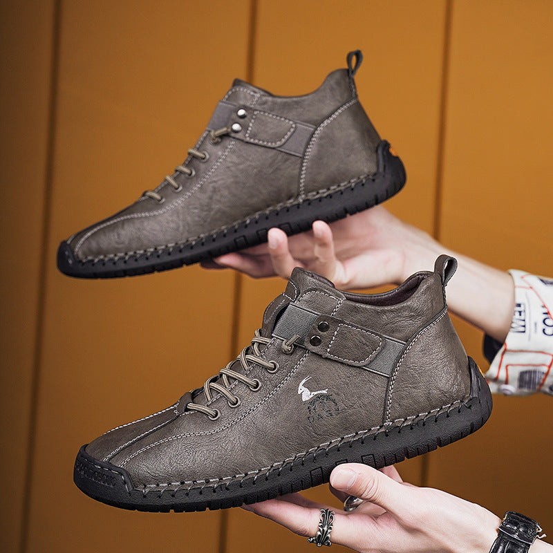 Two gray leather shoes held by hands against a wooden background