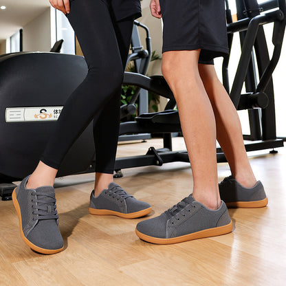 Two pairs of legs wearing gray sneakers with brown soles in a gym setting.