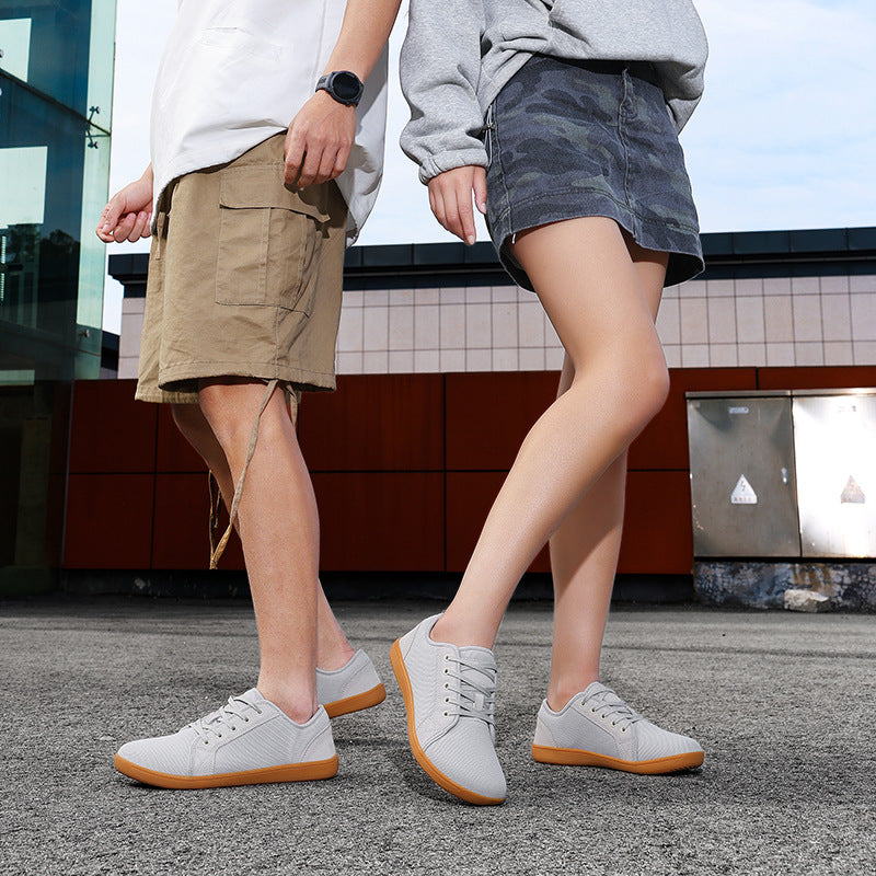 Two people wearing white sneakers with brown soles on a street.
