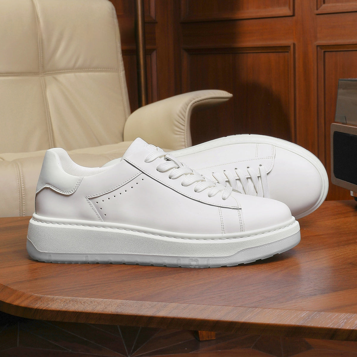 White sneakers on a wooden table with a beige chair in the background