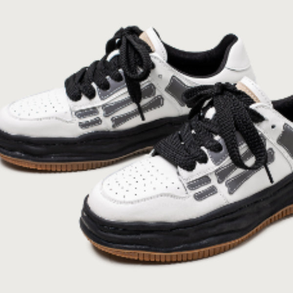 White sneakers with black and brown accents on a light gray background