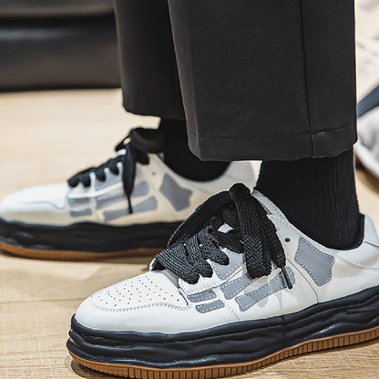 White sneakers with black and brown accents worn by a person on a wooden floor.