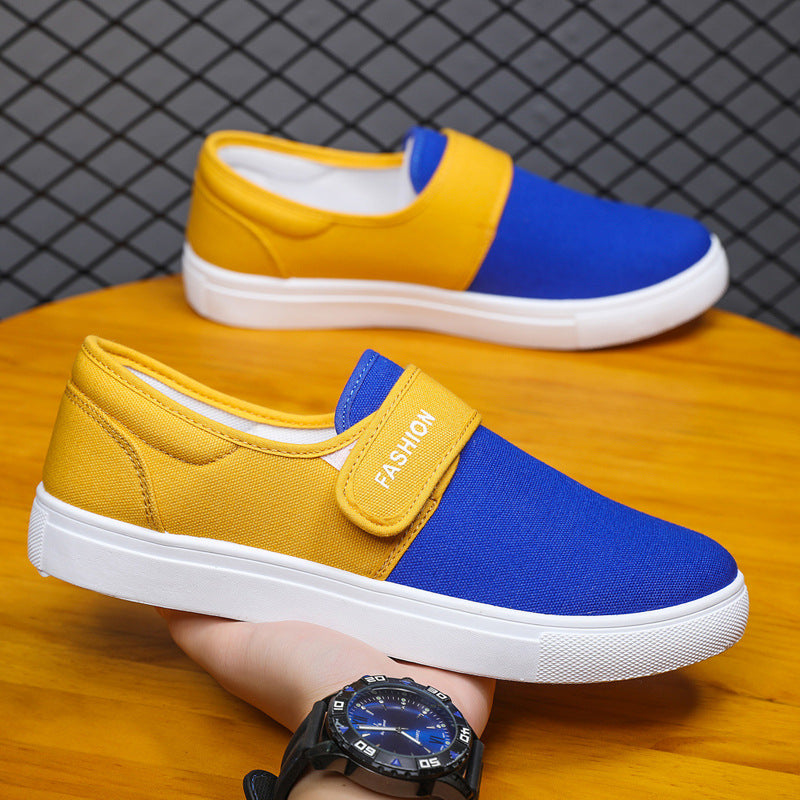 Yellow and blue slip-on shoes on a wooden surface with a grid-patterned wall in the background.