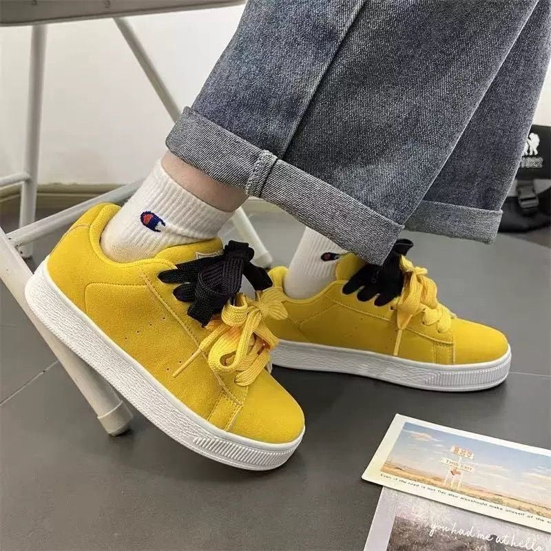 Yellow sneakers with black accents worn with rolled-up jeans and white socks.